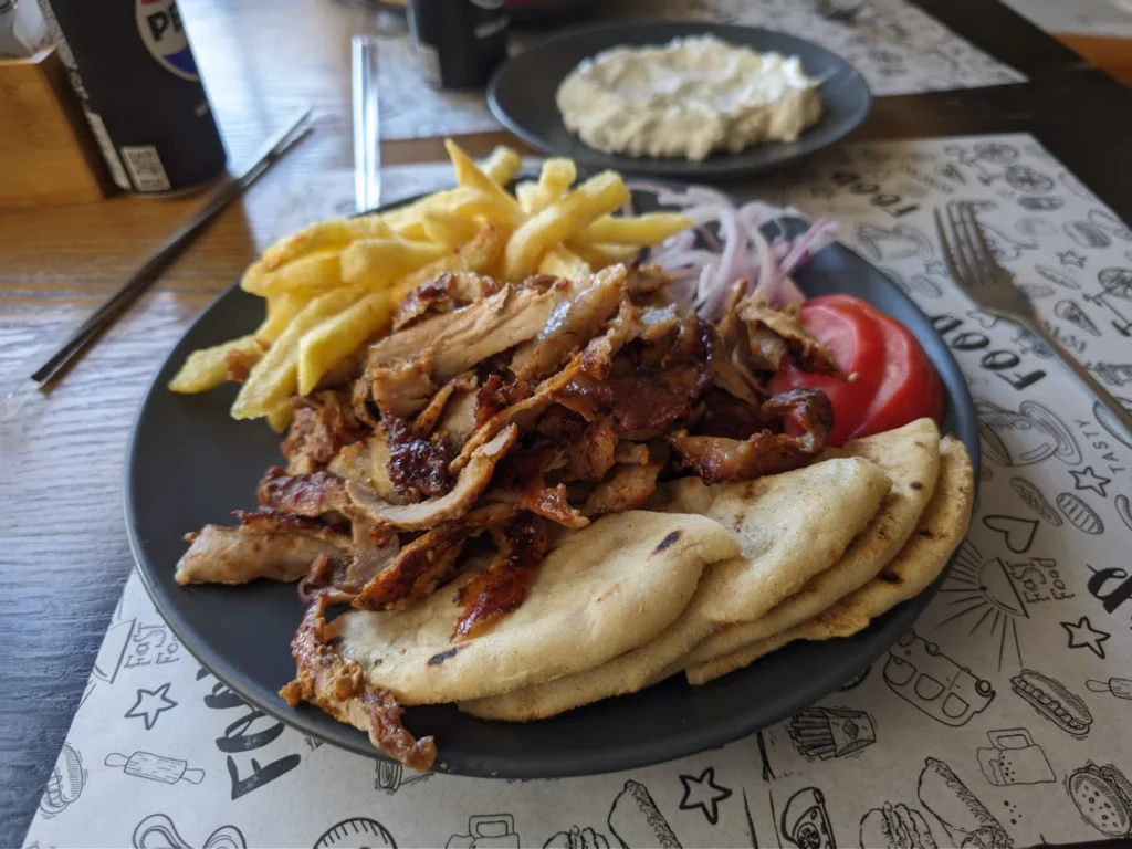 Gyros autentic din Salonic, servit cu pita pufoasă, carne suculentă, cartofi prăjiți și sos tzatziki.