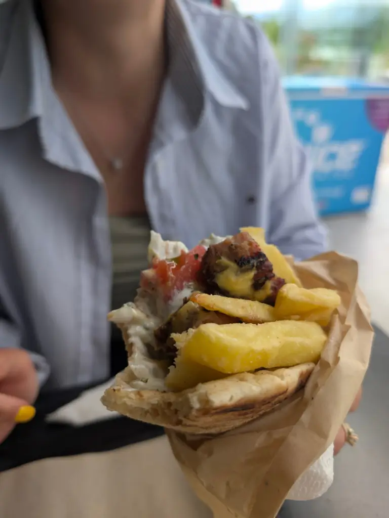 Deliciul Greciei: Souvlaki la popas, o experiență locală! O gustare savuroasă tip souvlaki/gyros, cu carne suculentă, tzatziki cremos și legume proaspete, perfectă pentru un popas rapid pe drumurile Greciei.