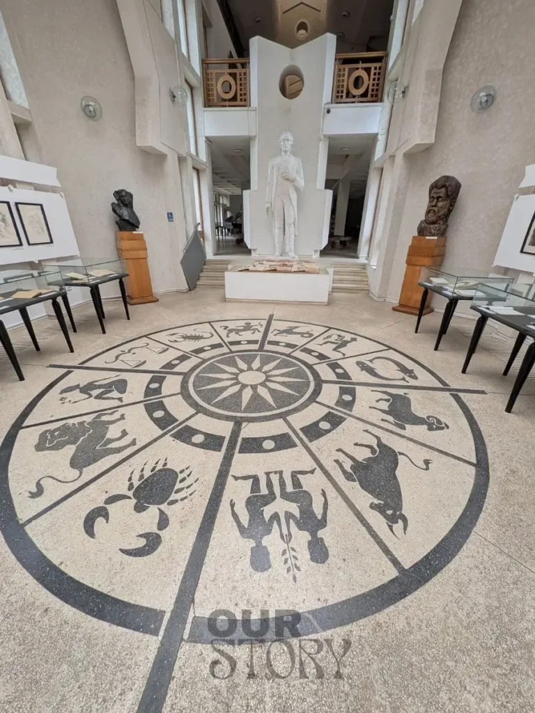 Interiorul Muzeului Mihai Eminescu Iasi cu zodiacul in mozaic pe podea si statuia poetului in centru - detaliu care arata pasiunea pentru astrologie, obiectiv turistic cultural.