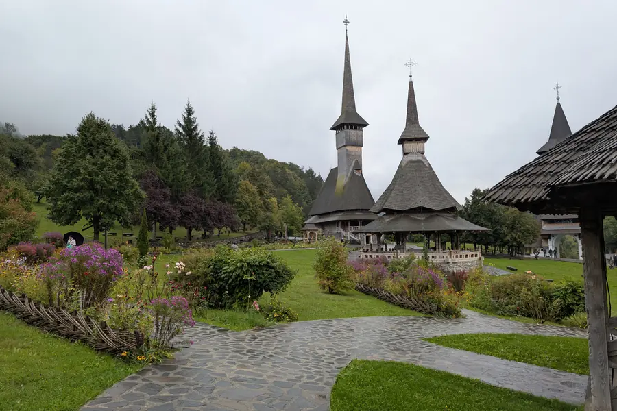 Mănăstirea Bârsana — turle ascuțite din lemn îmbătrânit, grădină cu flori, Valea Izei Maramureș
